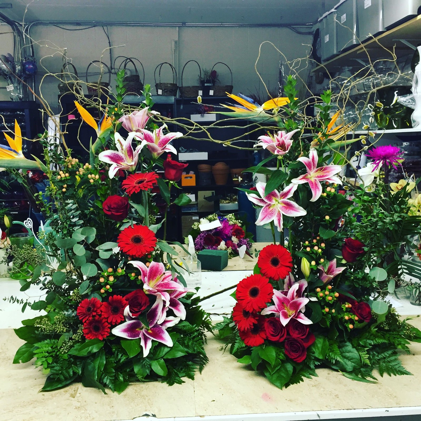 a beautiful urn spray made with red roses, stargazer lilies, birds